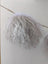 White curly mushroom sheepskin pom hanging from wooden stick