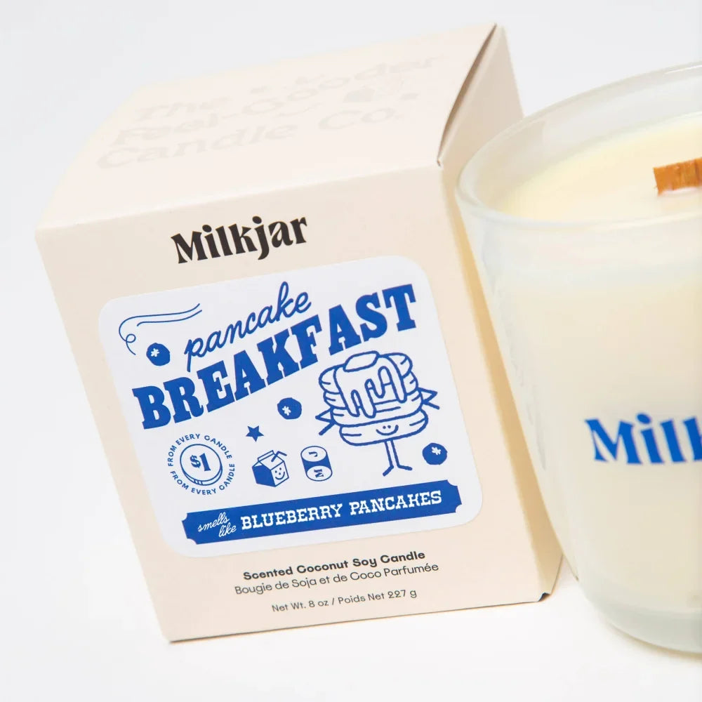 A creamy white soy candle with a wooden wick from milkjar scented like blueberry pancakes pancake breakfast blend