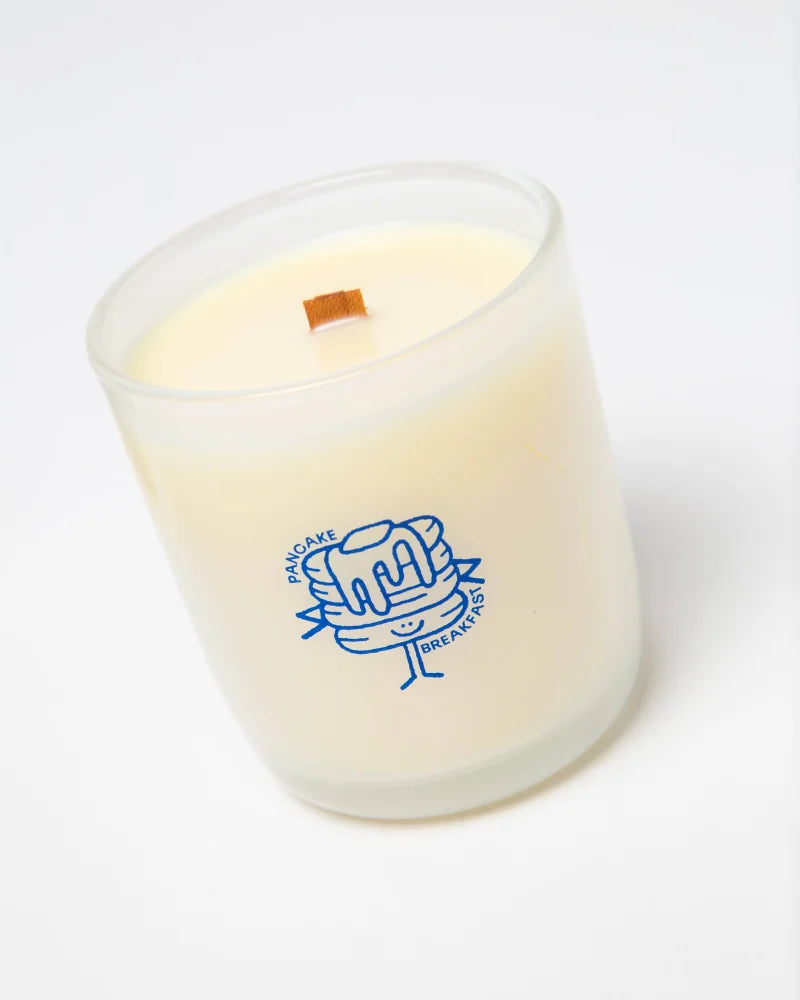A creamy white 8oz soy candle in a frosted jar with a blue pancake character labeled pancake breakfast