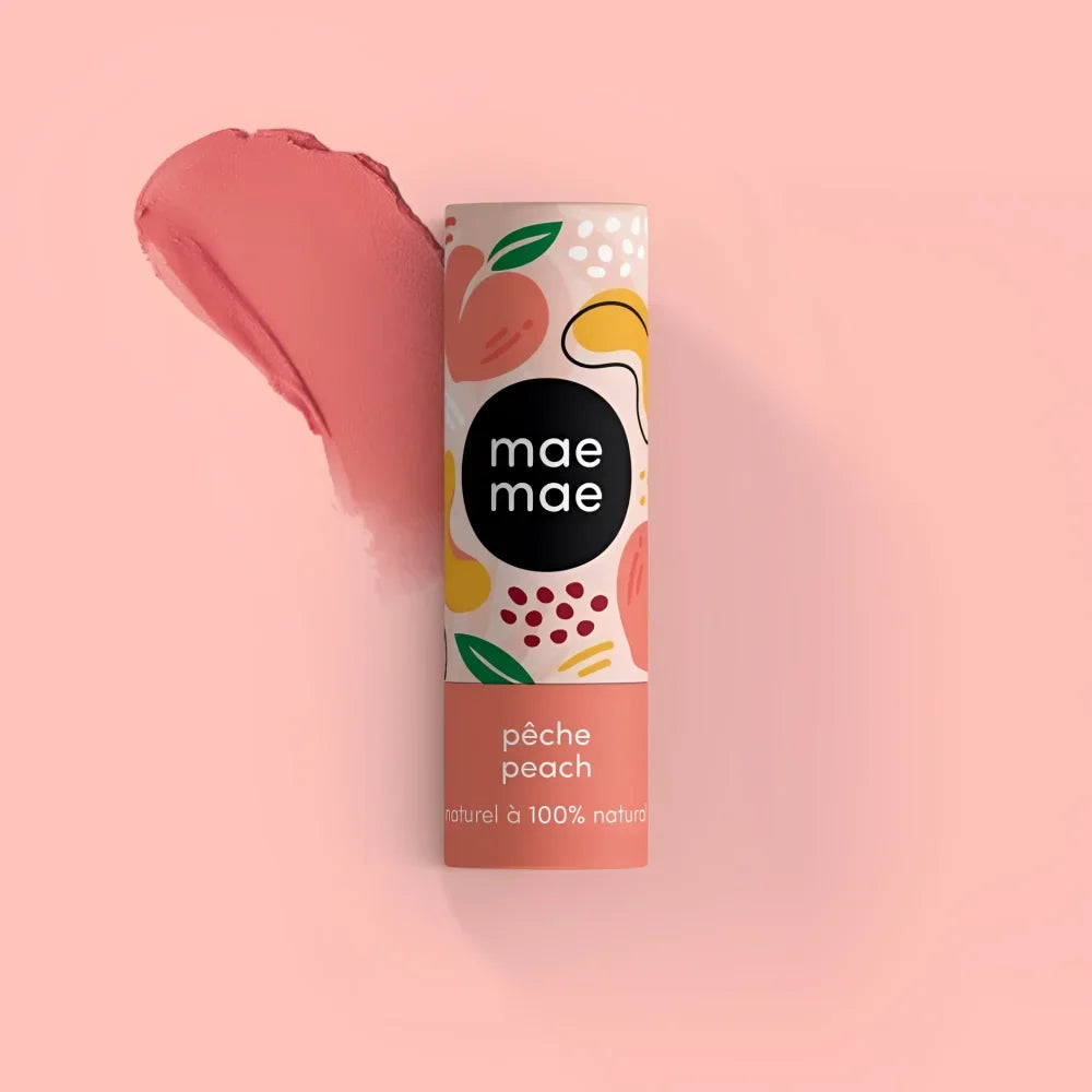 A peach-colored cylindrical mae mae lip balm tube with playful fruit design labeled pêche peach for natural lip tint