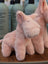 Soft pink plush pig toy with embroidered eyes and nose sitting on wood surface from large size pink piggies collection