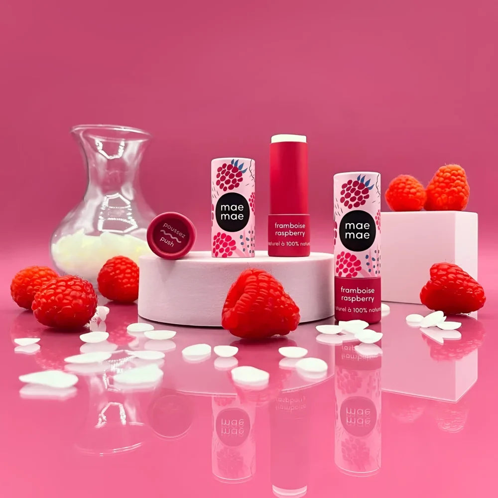 Three raspberry natural lip balms in sleek white and pink packaging with berry illustrations and a fresh scent