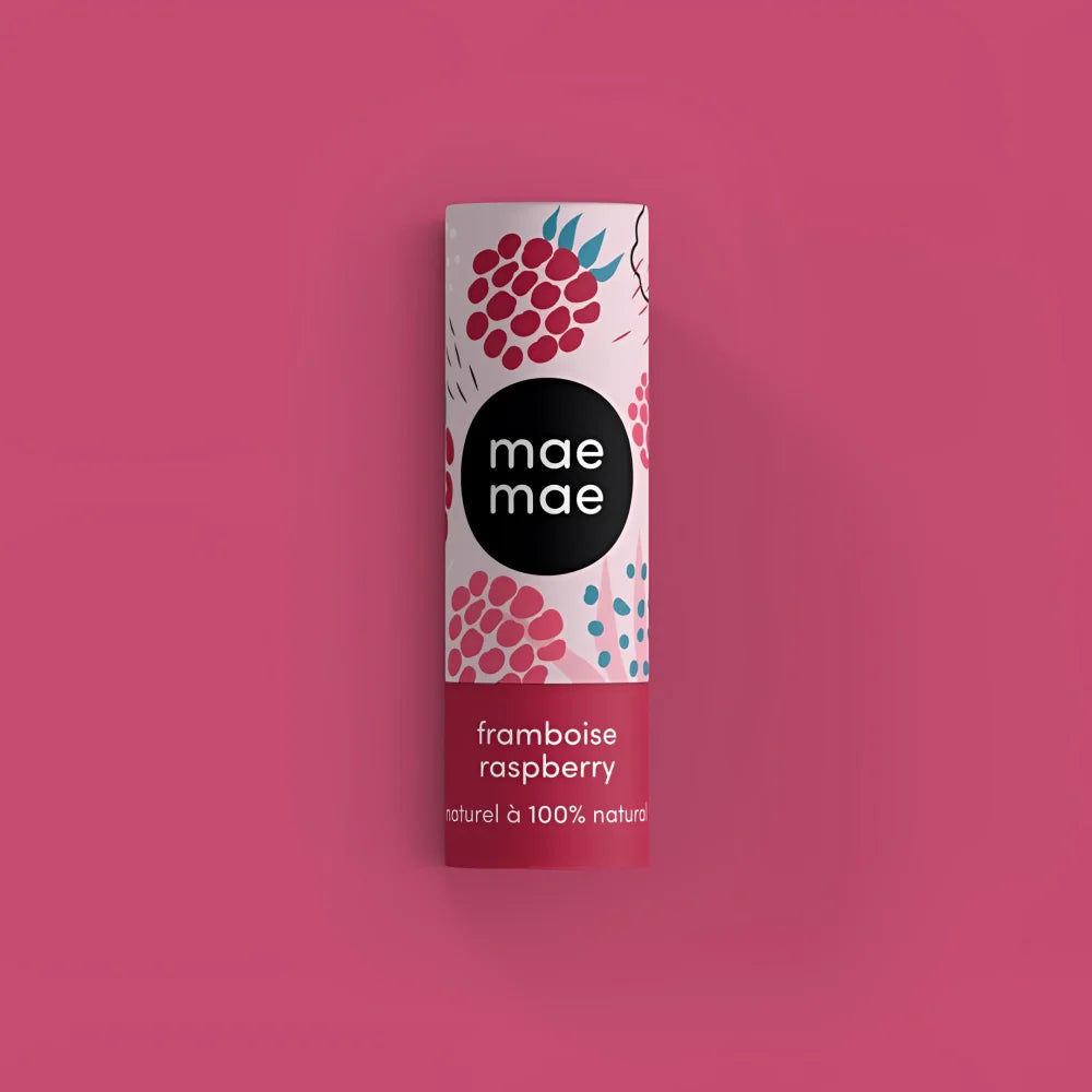 A cylindrical mae mae raspberry lip balm with white and pink label featuring raspberries on magenta background