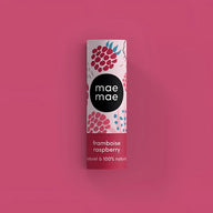 A cylindrical mae mae raspberry lip balm with white and pink label featuring raspberries on magenta background