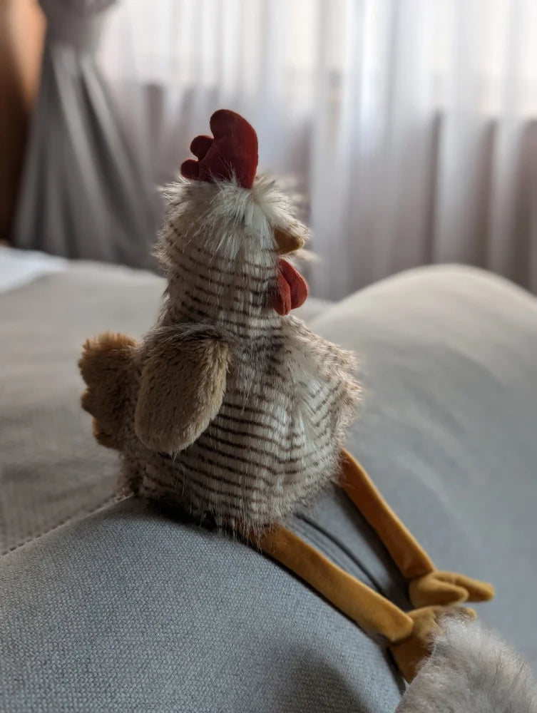 A plush chicken toy named rupert the rooster with a white and gray striped body by nana huchy