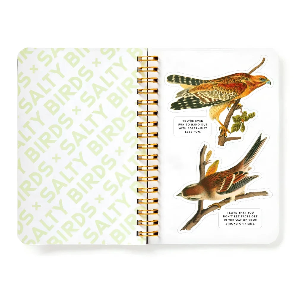 Open spiral-bound salty birds sticker book with gold binding and two illustrated bird stickers on a white page