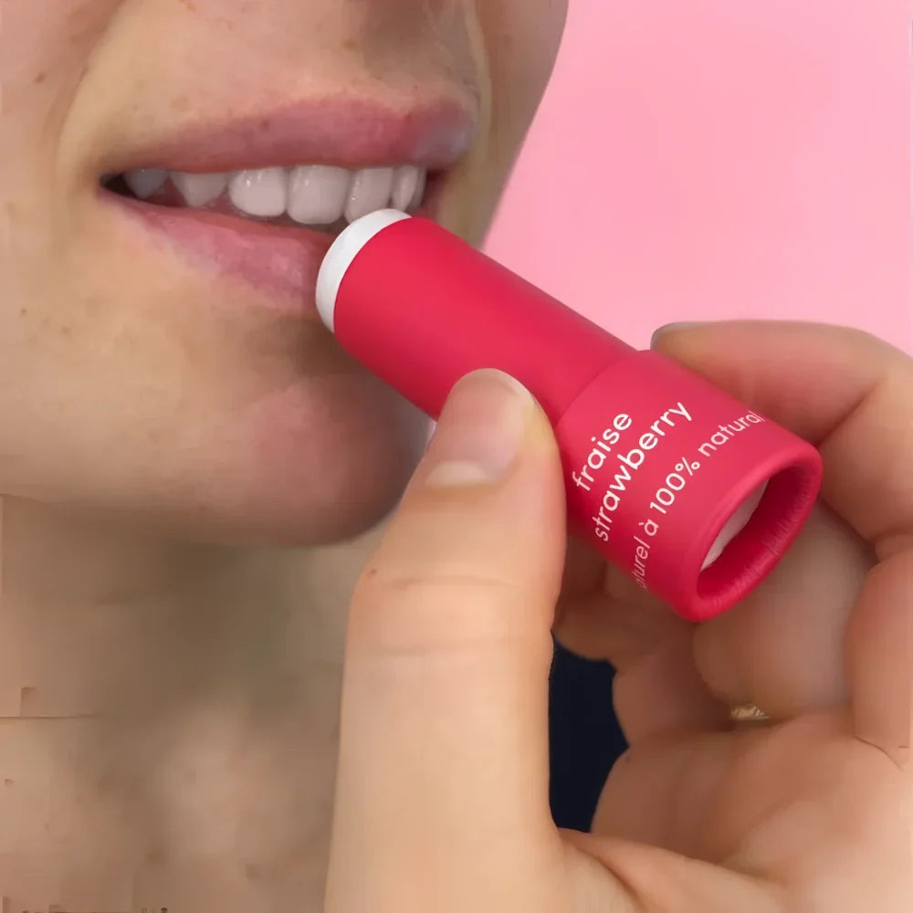 A vibrant red cylindrical strawberry scented lip balm tube with a white cap and minimalist branding for lip balms
