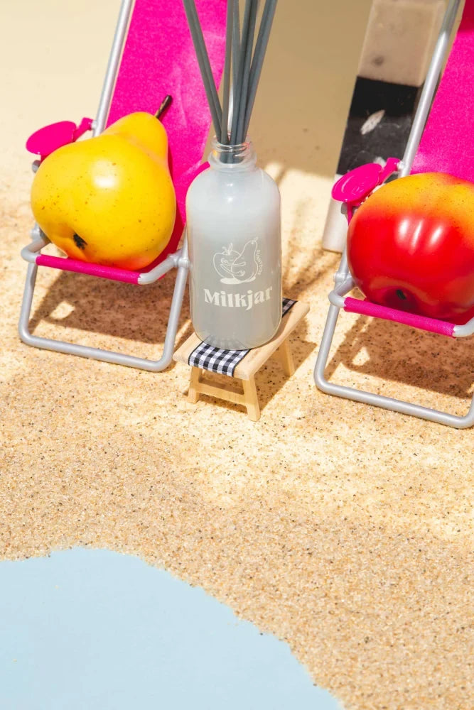 A frosted glass mluisjar reed diffuser bottle with dark gray sticks for pear and nectarine diffuser smells