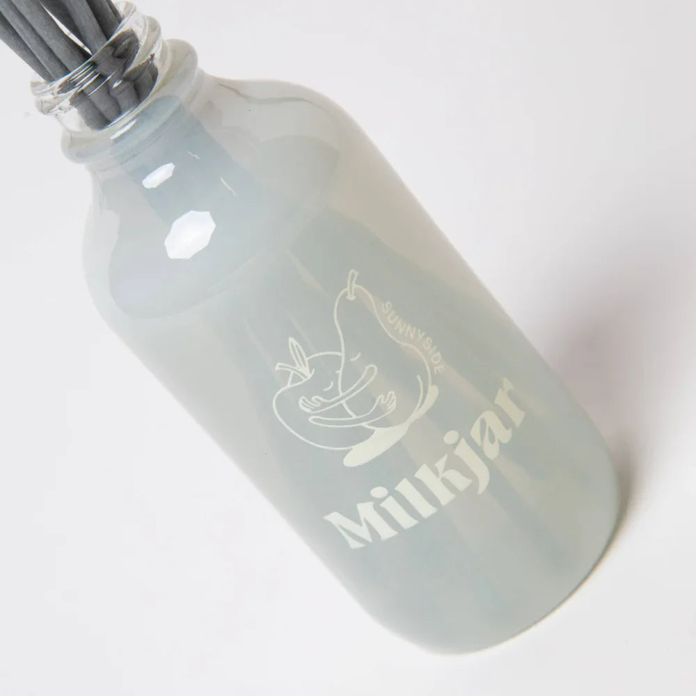 A frosted glass reed diffuser bottle with a pear etching and milkjar branding for diffuser smells in sunnyside scent