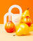 A creamy white coconut soy candle with a pink pear illustration nestled among yellow and red fruit sculptures