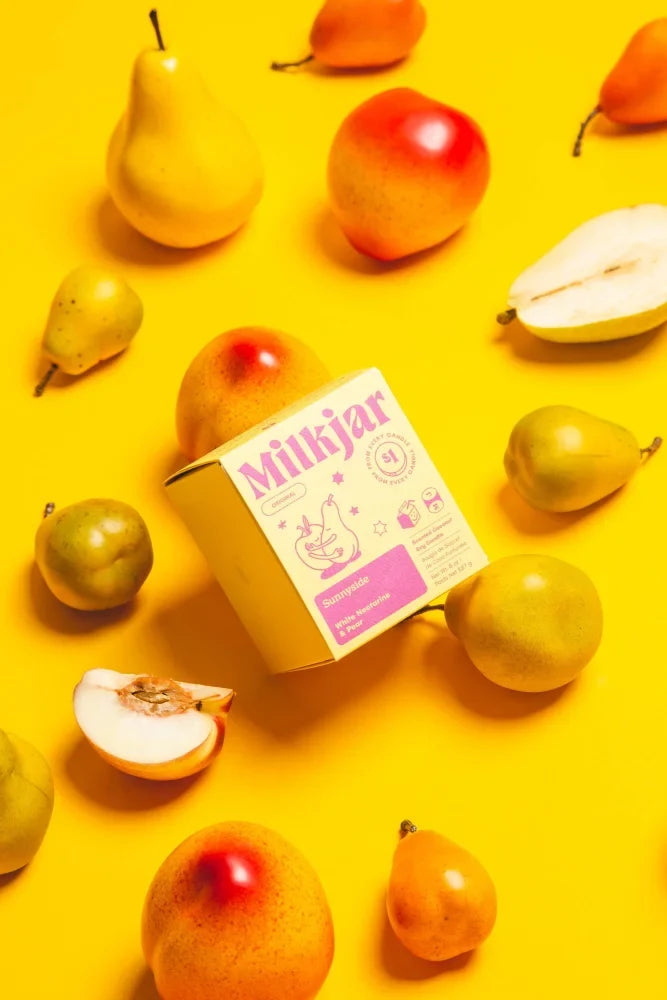 A pastel pink cream sunnyside pear nectarine coconut soy candle box with cute cartoon labeled strawberry flavor candle smells