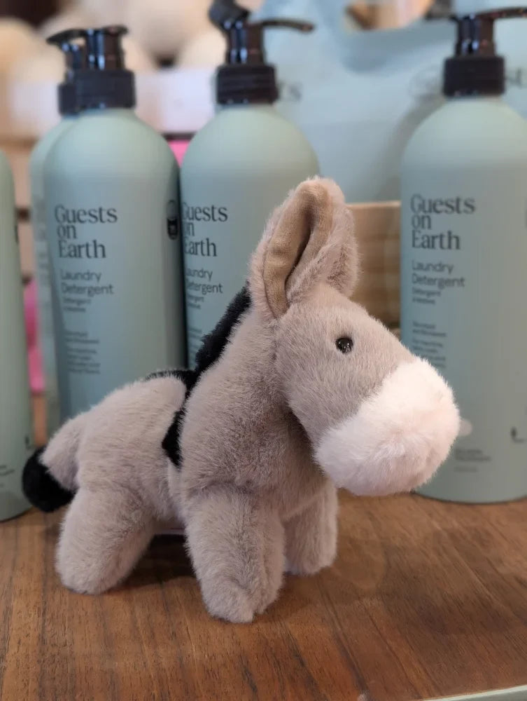 A soft plush donkey toy called the donkey with a tan body white muzzle and black ears and tail accents