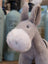 A soft gray plush donkey toy called the donkey with a fluffy white muzzle and black embroidered eyes