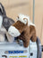 Brown plush horse with white mane and muzzle sitting on a gray techsew sewing machine in the pony product