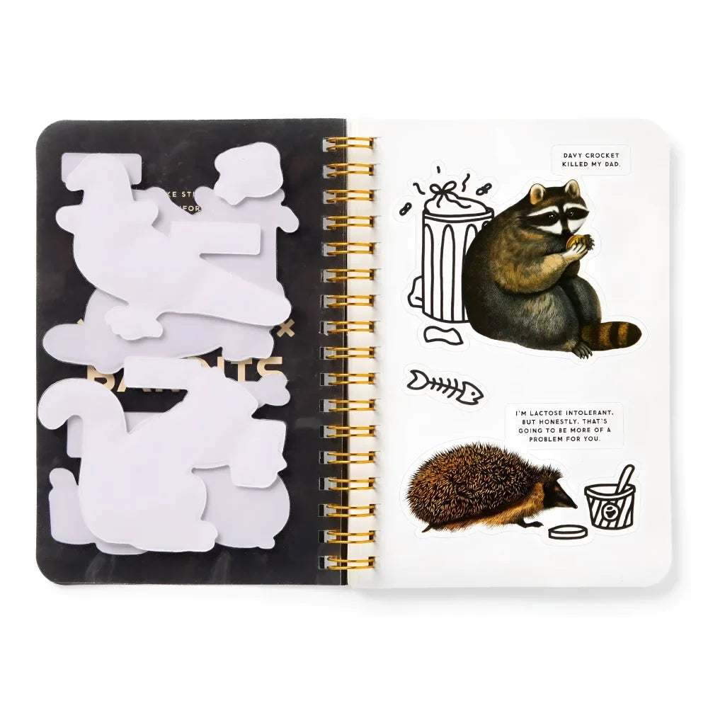 Black and white spiral notebook with trash bandits sticker featuring raccoon and hedgehog from trash bandits sticker book