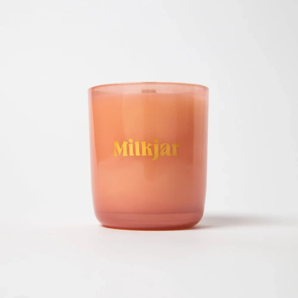 A peach frosted glass coconut soy candle jar with milkjar in gold lettering wallflower tobacco and peony scent