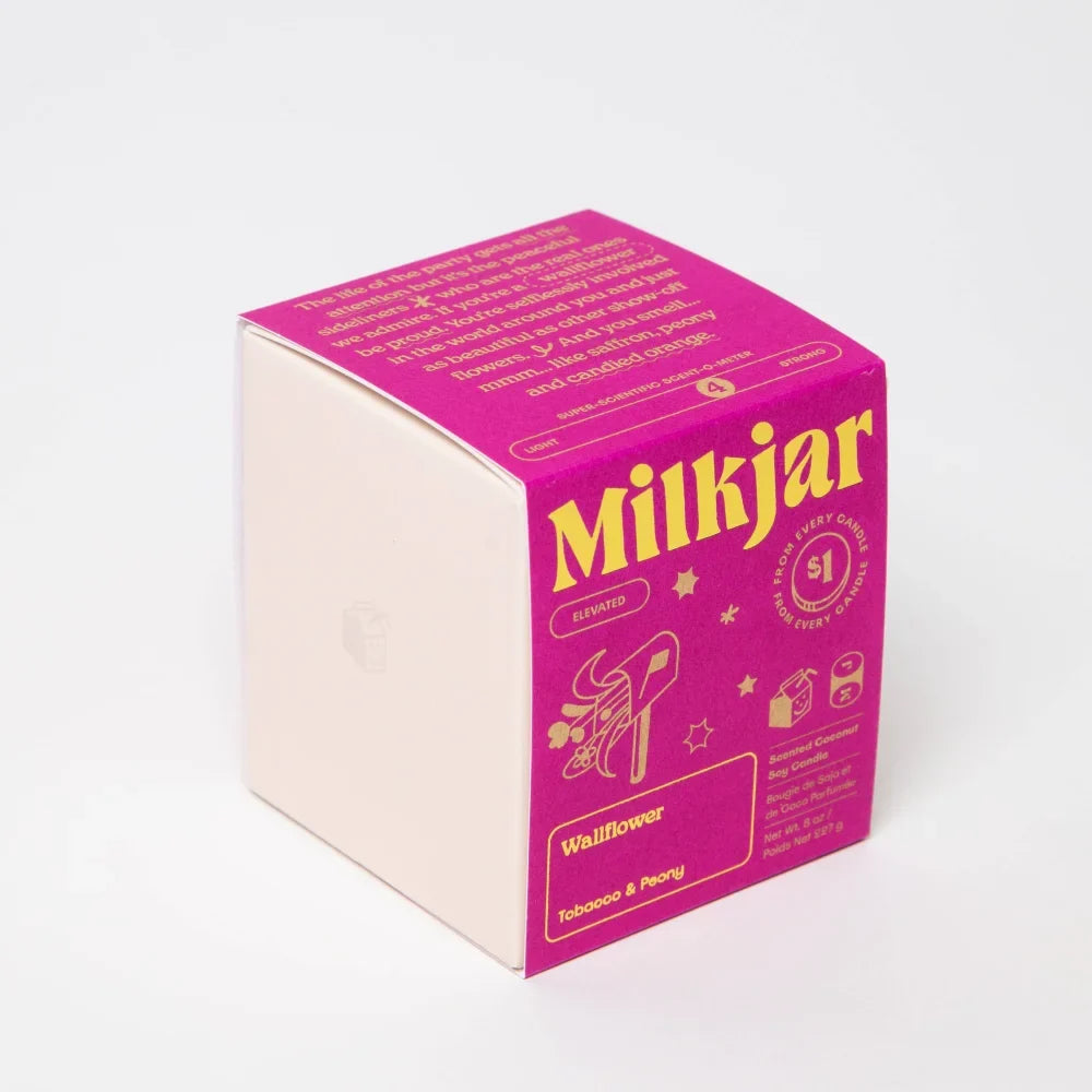 A vibrant pink and cream square box for wallflower tobacco and peony coconut soy candle with bold yellow lettering and flowers
