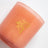 A peach-colored glass jar coconut soy candle with gold foil logo featuring floral design for wallflower tobacco peony