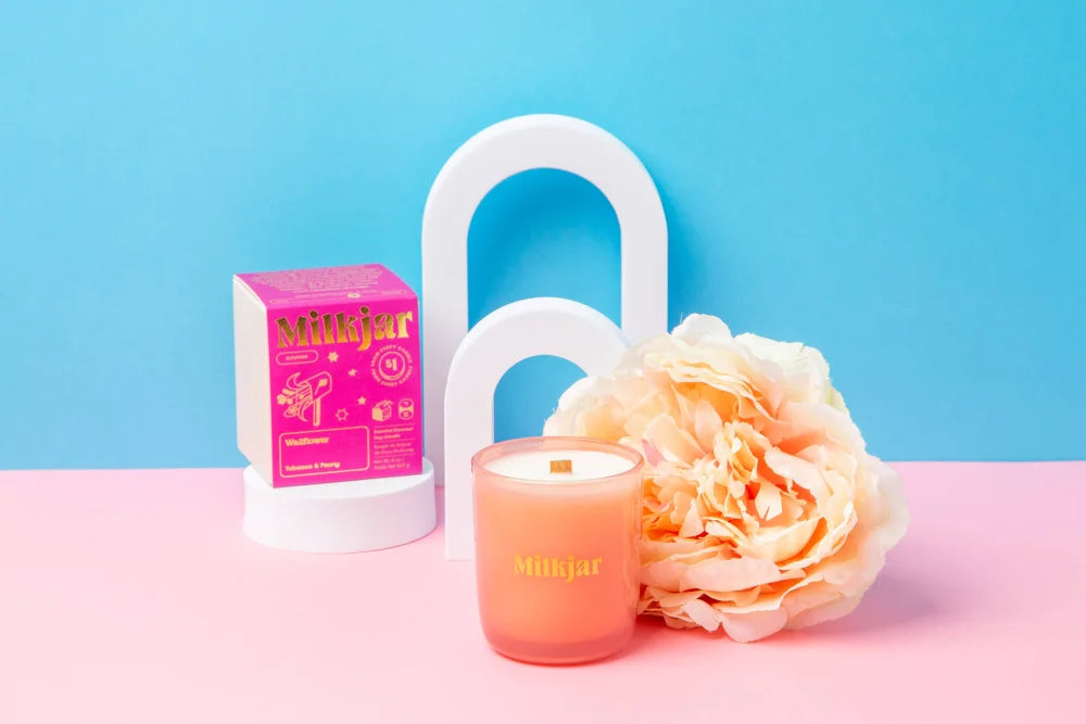 A peach-colored coconut soy candle with wooden wick by milkjar in tobacco and peony scent perfect for wallflower use