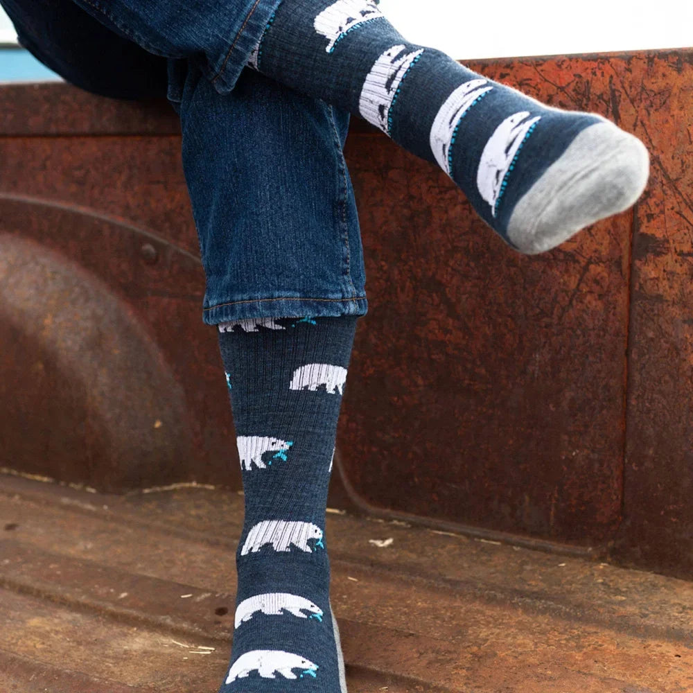 Women’s dark blue merino wool socks with white polar bear designs and teal accents worn with rolled-up denim jeans