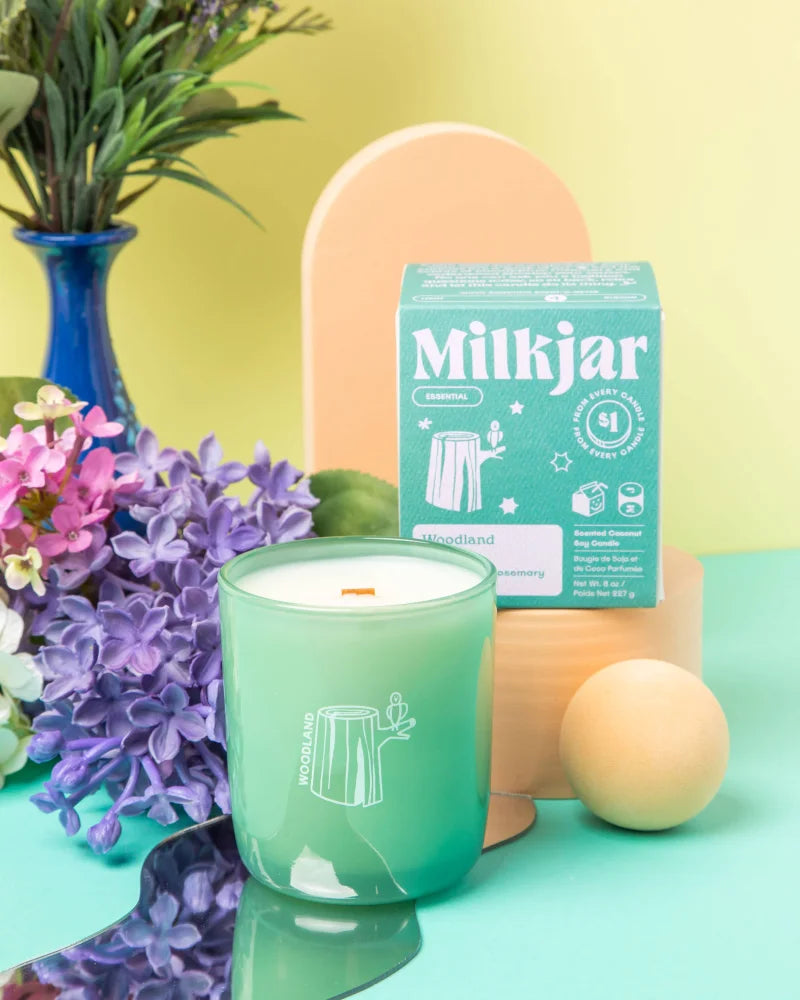 A mint green glass jar candle with white coconut soy wax and a minimalist tree stump design for essential oil use