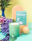 A mint green glass jar candle with white coconut soy wax and a minimalist tree stump design for essential oil use