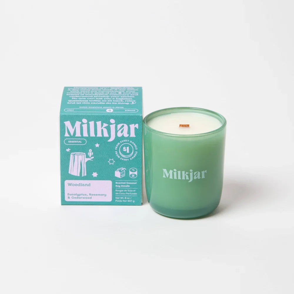 Milkjar woodland essential oil coconut soy candle in translucent sage green glass jar with white lettering