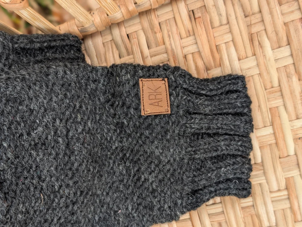 Dark gray knitted fingerless glove with brown leather patch and ark logo, perfect alongside your woolen calgary cardigan with attached hood made from zealand wool