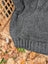 A cozy dark gray calgary cardigan in zealand wool with cable knit texture and ribbed cuffs, no attached hood visible
