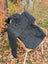Dark gray calgary cardigan woolen hoodie with zealand wool and attached hood resting on a wicker chair