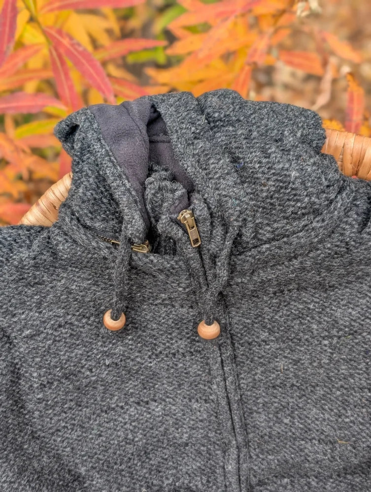 Cozy dark gray woolen calgary cardigan with attached hood, wooden toggle drawstrings, and brass zipper