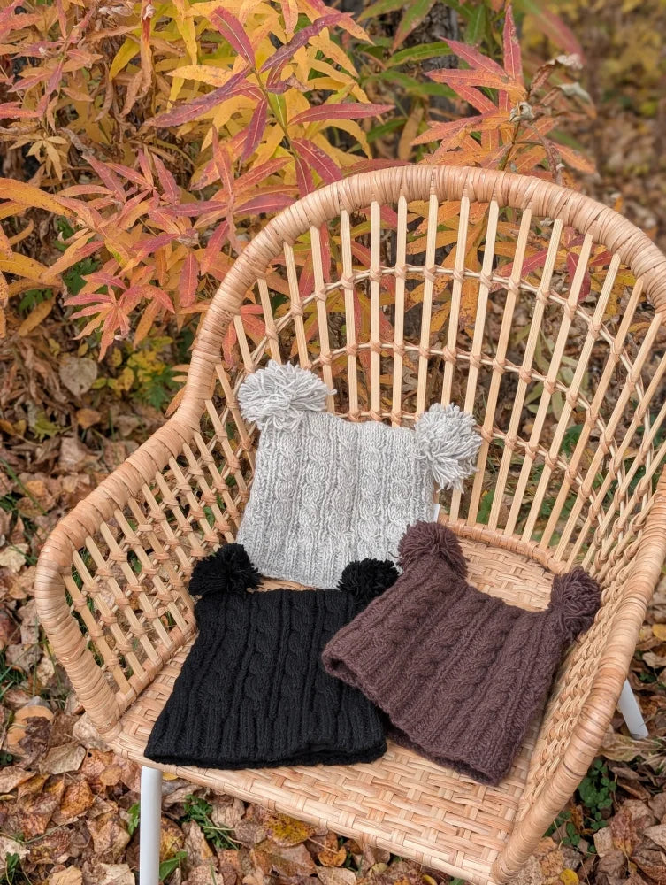 Three woolen heelah double pompom hats in gray black and brown with double pompoms perfect for cold weather