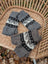 Gray knitted fingerless hand warmers with black and white geometric patterns made from fair trade zealand wool